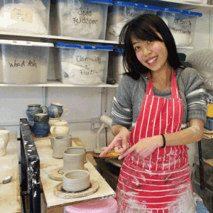 pottery student with completed pots made on a potters wheel