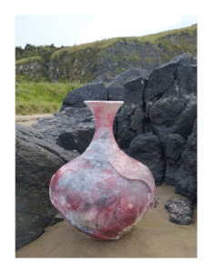 vessel made by pit firing with smoky surface photographed in front of black rocks on Downhill Beach Northern Ireland